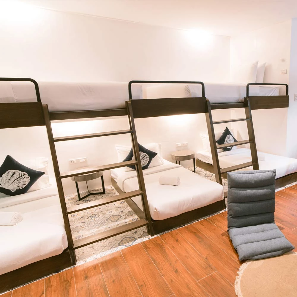 Family Room · Family room with three wooden bunk beds made up in white linen and floor cushions on a wooden floor · Photo 1 of 5