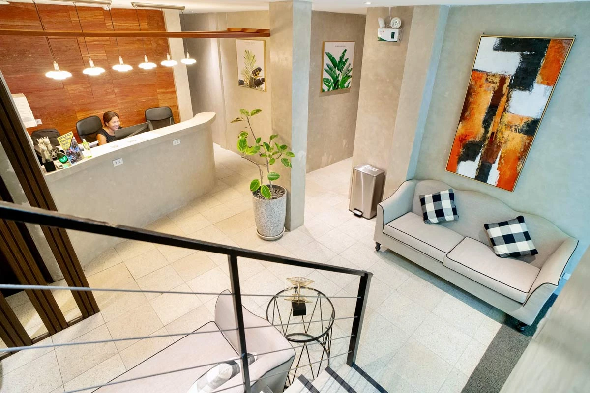 Reception desk and lounge with a grey sofa, black-and-white cushions and an abstract painting